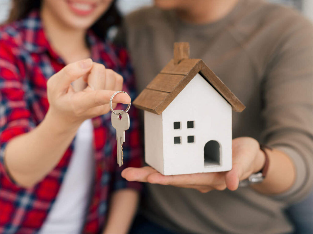 image of couple with a miniature house and house key representing buying a house