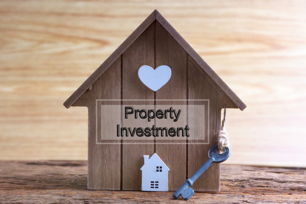 image of a miniature woden house with a key hanging on the side and text saying Property Investment